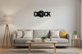 Black 'CLOCK' wall clock on a white wall above a desk with office supplies.